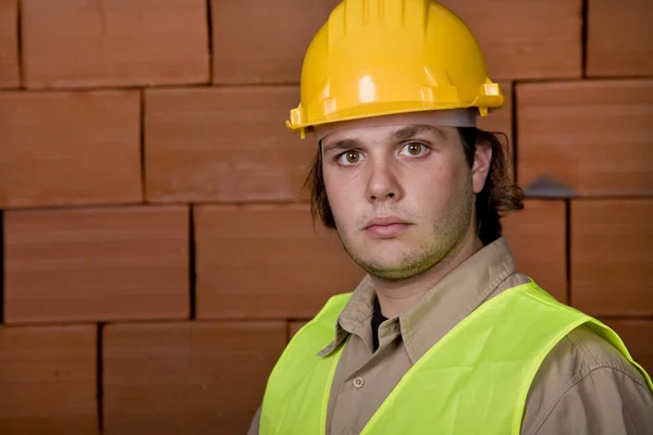 Ingeniero con sombrero amarillo con una pared de ladrillo como fondo —  Fotos de Stock