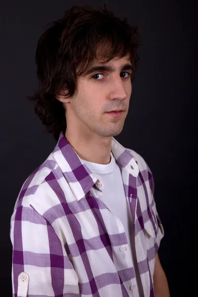 Young casual man against a black background — Stock Photo, Image