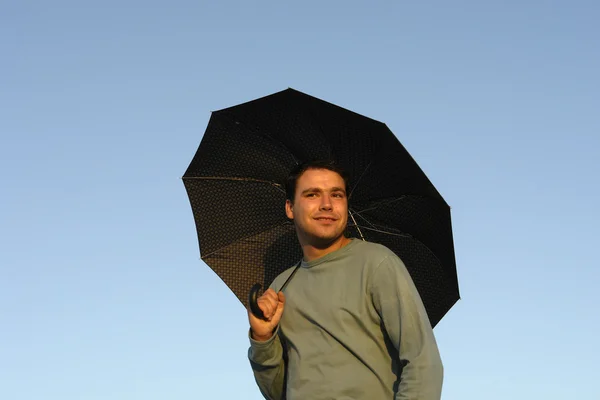 Young man with umbrella at sunset light — Stock Photo, Image