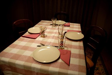 Dinner table ready to serve in a dark room clipart