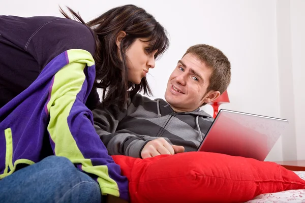 Joven pareja feliz en la cama con el ordenador portátil — Foto de Stock