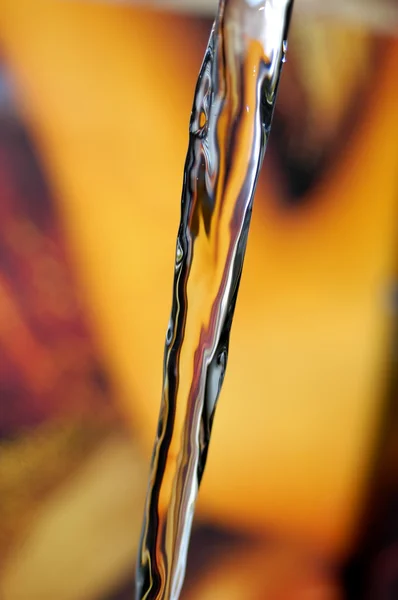 Detalhe do fluxo de água em um fundo colorido — Fotografia de Stock