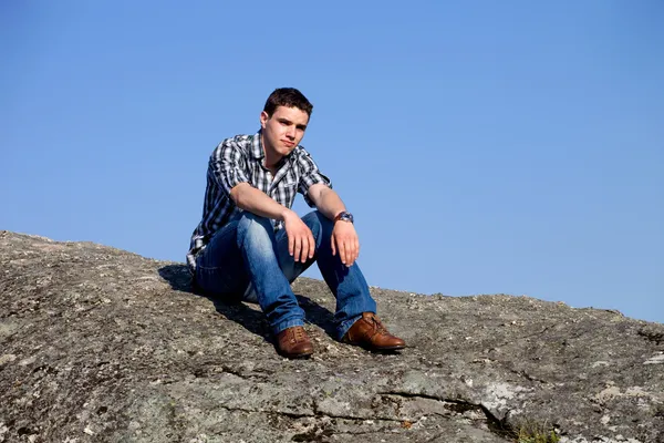 Joven hombre casual en la parte superior de una roca — Foto de Stock