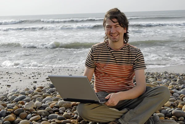 Jovem na praia com laptop — Fotografia de Stock