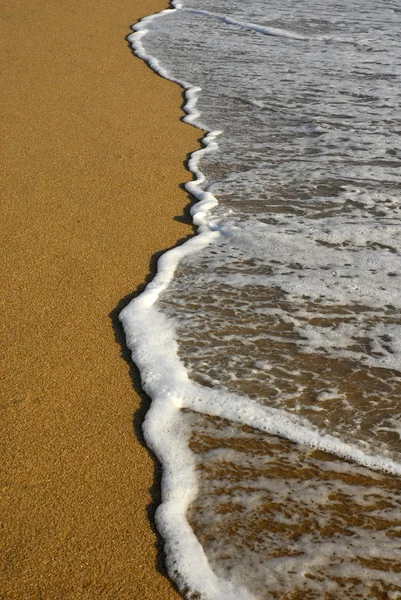 Белая волна в песке на пляже — стоковое фото