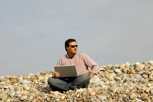 Junger lässiger Mann mit Laptop am Strand — Stockfoto