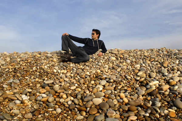 Neformální mladý muž na pláži kameny — Stock fotografie