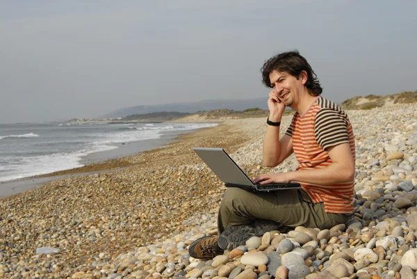 Young man at the beach with laptop — Stock Photo, Image