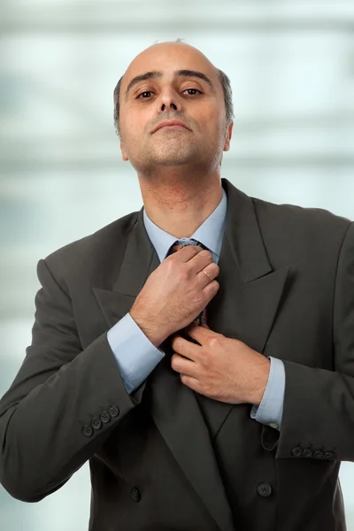 A mature business man adjusting his tie — Stock Photo, Image