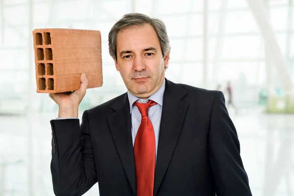 Mature business man with a big brick — Stock Photo, Image