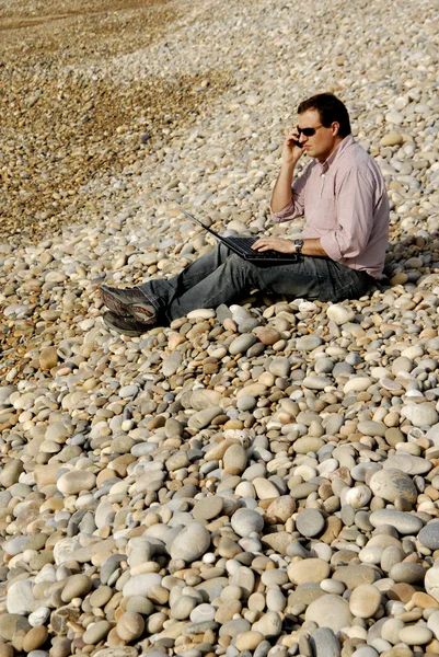 Příležitostné mladík s notebookem na pláži — Stock fotografie