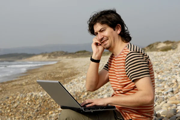 Giovane in spiaggia con computer portatile — Foto Stock