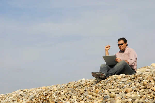 Junger lässiger Mann mit Laptop am Strand — Stockfoto