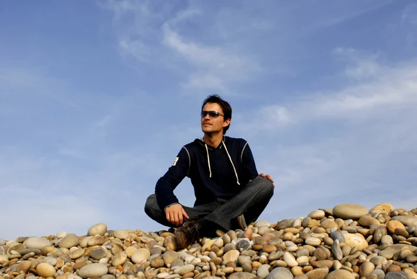 Joven hombre casual en las piedras de la playa — Foto de Stock