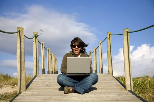 Bilgisayar ile plajda çalışan genç kadın — Stok fotoğraf