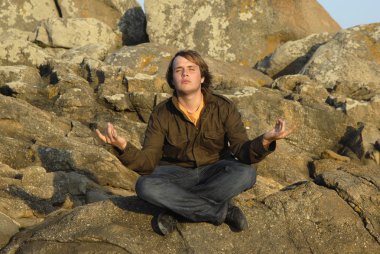 genç adam kayalar üzerinde otururken meditasyon