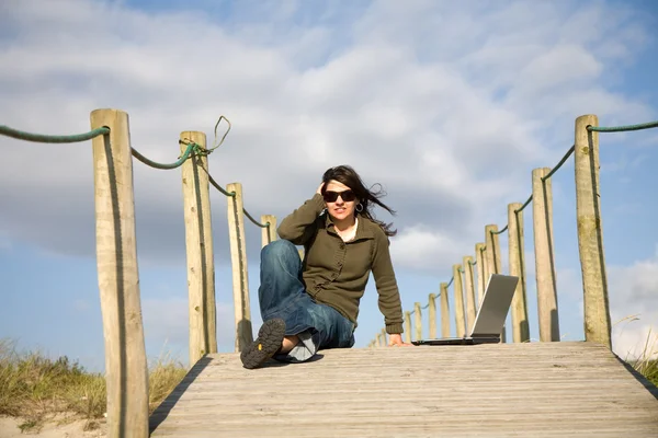 Mujer joven que trabaja con computadora en la playa — Foto de Stock