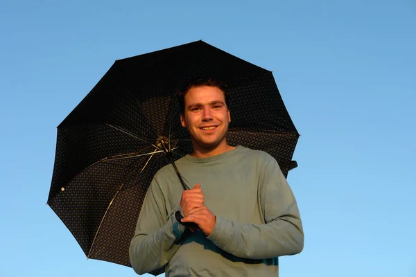 Young man with umbrella at sunset light — Stock Photo, Image