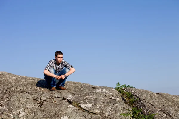 Joven hombre casual en la parte superior de una roca — Foto de Stock