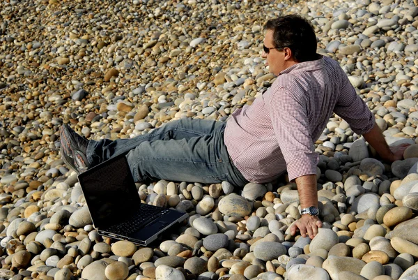 Young casual man with laptop at the beach — Stock Photo, Image
