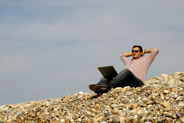 Jeune homme décontracté avec ordinateur portable à la plage — Photo