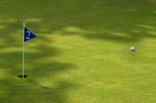 М'яч і прапор у зеленому полі для гольфу — стокове фото