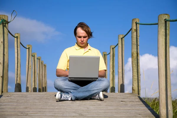 若い男が浜のコンピューターでの作業 — ストック写真
