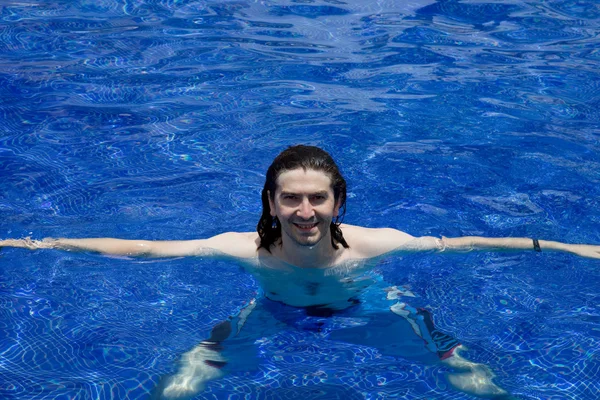 Mladík šťastný úsměv na bazén s jasně modrou vodou — Stock fotografie