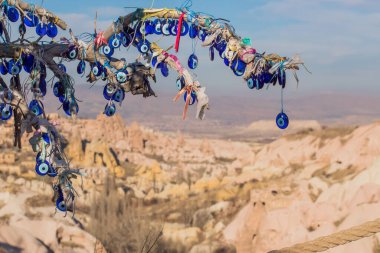 Türkiye 'nin Kapadokya kentindeki Kumlu Dağ' ın önündeki ağaçta asılı duran nazar boncuklarına karşı madalyonlar