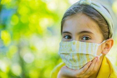 Corona virüsüne karşı maske takan küçük bir kız.