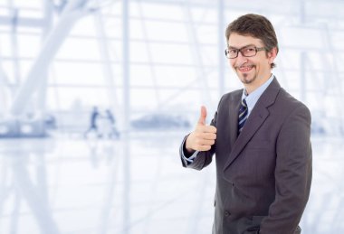 Genç iş adamı ofiste başparmağını kaldırıyor.