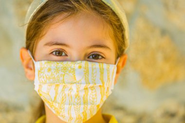 Corona virüsüne karşı maske takan küçük bir kız.