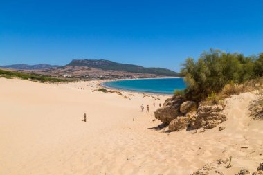 Tarifa, İspanya. Turistler, Cadiz 'deki Tarifa' nın bozulmamış beyaz kumlu plajı Playa de Bolonia Plajı 'na doğru yürüyorlar. Endülüs, İspanya.
