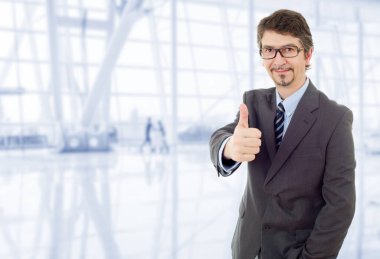 Genç iş adamı ofiste başparmağını kaldırıyor.