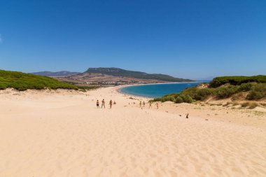 Tarifa, İspanya. Turistler, Cadiz 'deki Tarifa' nın bozulmamış beyaz kumlu plajı Playa de Bolonia Plajı 'na doğru yürüyorlar. Endülüs, İspanya.