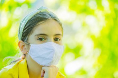 Corona virüsüne karşı maske takan küçük bir kız.