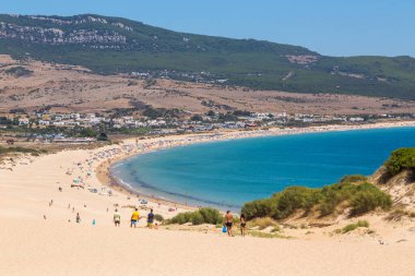 Tarifa, İspanya. Turistler, Cadiz 'deki Tarifa' nın bozulmamış beyaz kumlu plajı Playa de Bolonia Plajı 'na doğru yürüyorlar. Endülüs, İspanya.