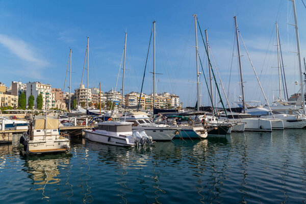 Греция, Афины. Пришвартованные яхты удовольствия и рыбацкие лодки в порту Пирей. Теплый солнечный день у моря в Греции.