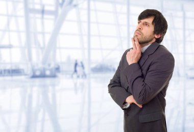 Genç bir iş adamı, ofiste düşünüyor.