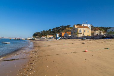Trafaria, Portugal: Houses and bars along the seafront with wooden boats and pollutio at Trafaria, Portugal