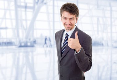 Genç iş adamı ofiste başparmağını kaldırıyor.