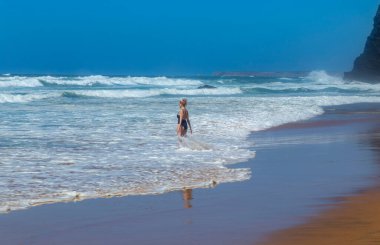 Sagres, Portekiz: Dalgaların arasında plajda yoga yapan rahat bir kadın. Sagres, Algarve. Portekiz