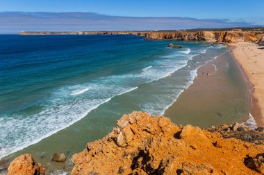 Sagres, Portekiz: Portekiz 'in Algarve kentindeki Sagres köyü yakınlarındaki kumlu plajda sörfçülerin görüntüsü