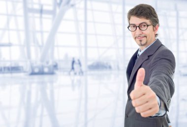 Genç iş adamı ofiste başparmağını kaldırıyor.