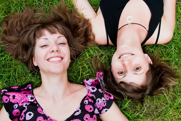 Two women lie on a green grass — Stock Photo, Image