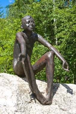 bir taş üzerinde oturan erkek heykeli