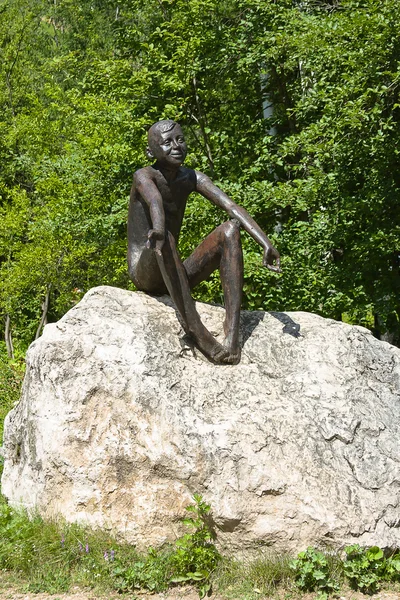 Sculptuur van jongen zittend op een steen — Stockfoto