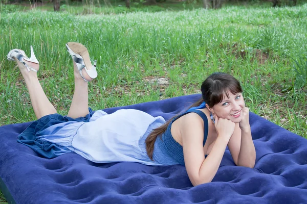 Mulher bonita na natureza encontra-se em um colchão inflável — Fotografia de Stock