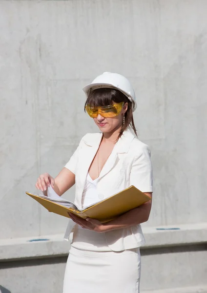 Mulher em um capacete e por documentos em mãos — Fotografia de Stock