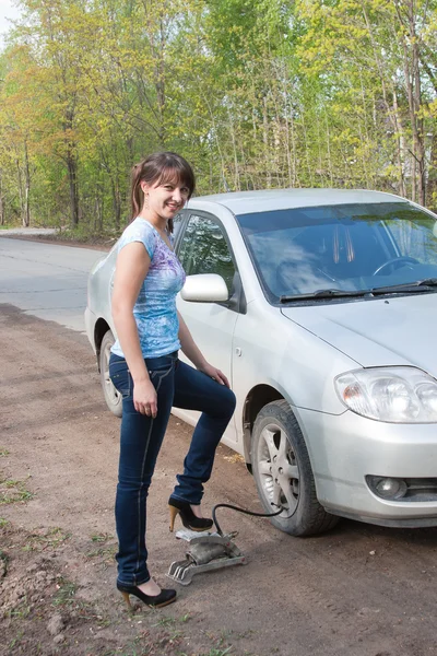 Woman a driver pumps full a wheel at a car — Stock Photo, Image